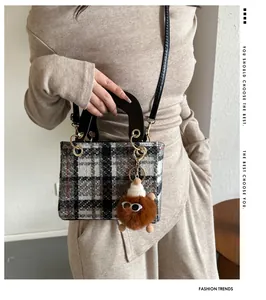 Detail of tweed houndstooth crossbody bag with gold rings and brown plush charm