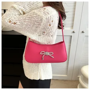 Detail of rose pink underarm bag featuring a sparkling silver rhinestone bow decoration