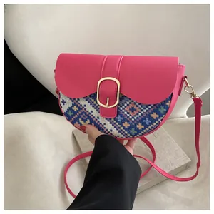 Detail of rose pink saddle bag featuring ethnic woven pattern and gold horseshoe buckle