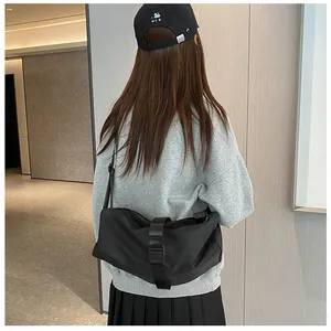 Detailweergave van de zwarte nylon crossbodytas gedragen over een grijze sweatshirt