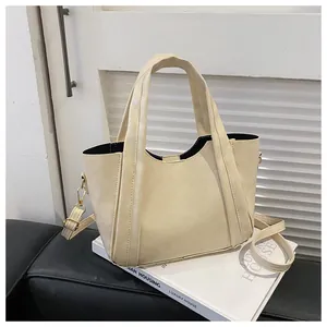 Detail of off-white tote bag with gold hardware, textured vertical lines and shoulder strap