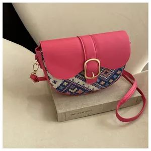 Detail of magenta leather saddle bag with ethnic woven pattern and gold horseshoe buckle