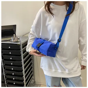 Detailweergave van een helderblauwe oxford crossbodytas met zwarte gesp en brede riem