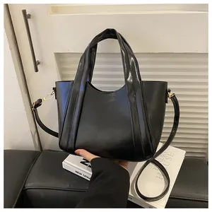 Close-up of black pleated bucket bag featuring elegant gold metal buckles and slim strap
