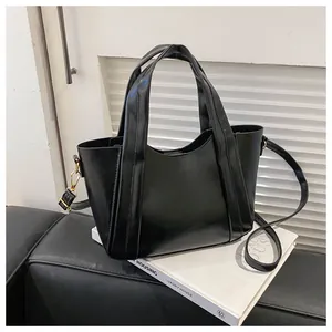 Detail of black glossy tote bag with gold hardware on a leather chair setting