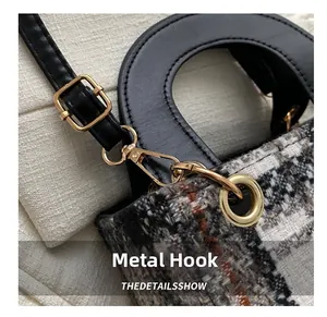 Detailed close-up of golden hardware hook and textured houndstooth tweed fabric for tote bag
