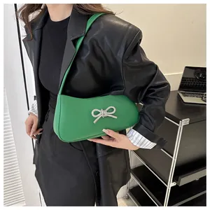 Close-up of green leather shoulder bag with a sparkling diamond bow buckle detail