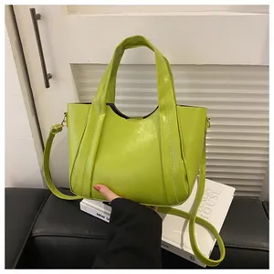Detail of bright green patent leather handbag with gold hardware and top handle