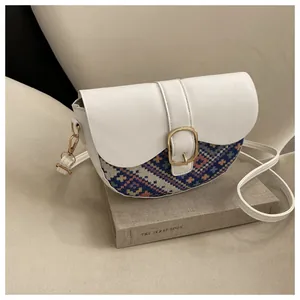 Close-up of saddle bag with white leather and colorful geometric ethnic woven fabric