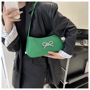Emerald green underarm bag with a crystal-embellished bow detail on high-quality leather
