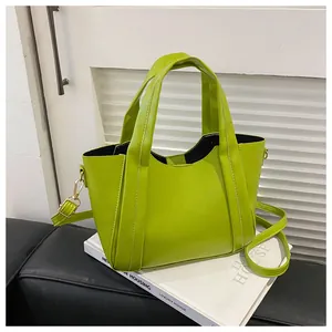 Detail view of glossy bright green PU leather bucket bag with gold metal hardware and strap