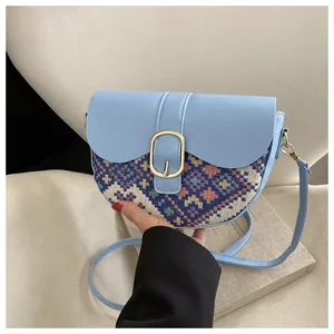 Detail of light blue saddle bag featuring ethnic geometric fabric and gold buckle