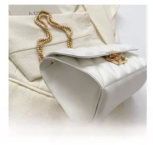 Gros plan du sac à main blanc matelassé avec boucle dorée et bandoulière en chaîne