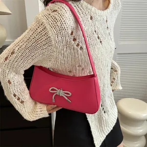 Magenta bow baguette bag with silver rhinestone detail shown as a shoulder underarm bag