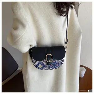 Detail of ethnic style patchwork saddle bag for women worn with a stylish white coat