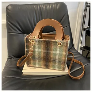 Detail of vintage tweed houndstooth crossbody bag with brown leather handle and gold hardware