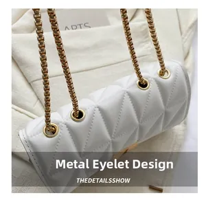 Détail des œillets métalliques et des chaînes dorées sur le sac matelassé blanc