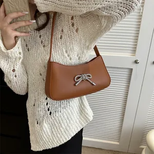 Brown leather baguette bag with a sparkling rhinestone bow detail for elegant shoulder wear