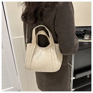 French minimalist chic bucket bag in beige leather shown on a shoulder in daily context