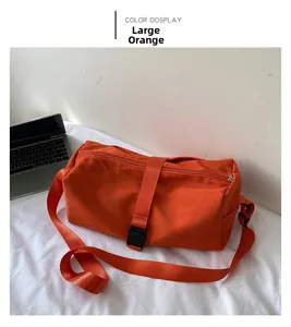 Bolso bandolera de nailon naranja grande con correa junto a un portátil en el escritorio