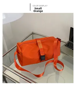 Primer plano del pequeño bolso bandolera naranja de tela Oxford con correa ajustable en mesa