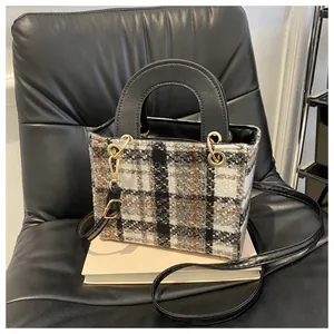 Detail of tweed houndstooth crossbody bag with leather handles and gold metal accents