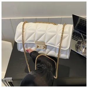 Détail de la texture matelassée blanche avec chaîne dorée et fermoir pivotant