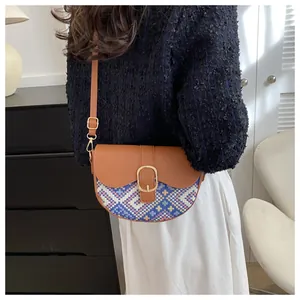 Detail of ethnic style saddle bag with blue geometric pattern and gold buckle