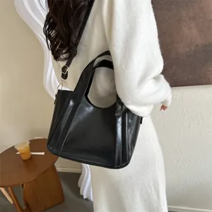 Glossy black leather bucket bag with top handle and gold hardware for women