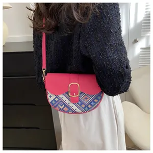 Detail of pink patchwork saddle bag featuring ethnic woven pattern and gold metal buckle