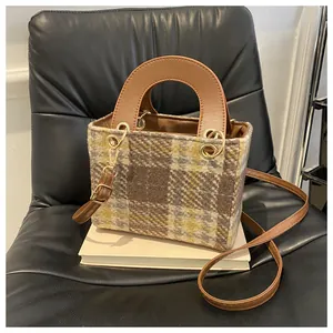 Close-up of checkered wool bag texture with leather handle and gold hardware detail