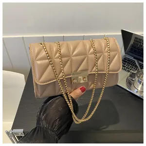 Détail de sac bandoulière matelassé beige avec chaîne dorée et fermoir métallique carré