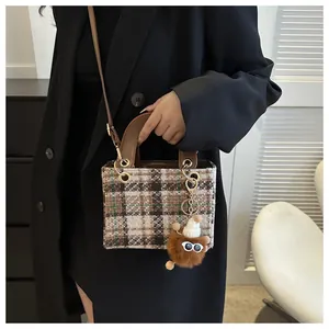 Detail of tweed houndstooth crossbody bag with plush charm and gold hardware