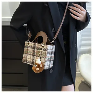 Close-up of brown houndstooth tweed bag with leather handle and plush bear charm