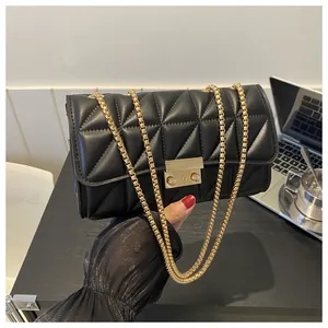 Détail d'un sac à bandoulière matelassé noir avec boucle dorée et chaîne métallique