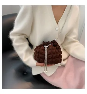 Details der dunkelbraunen Eimertasche mit Blasenstruktur, Silberkette und Perlen