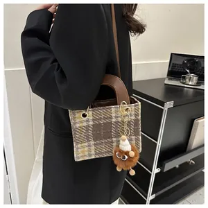 Detail of wool houndstooth crossbody bag with plush charm and leather handle