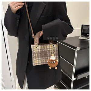 Close-up of houndstooth tweed handbag with leather handle and cute monster charm detail