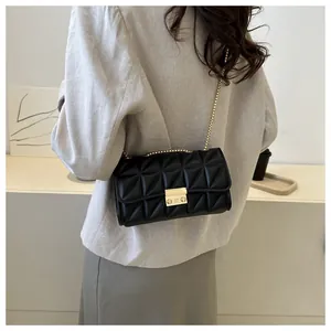 Détail d'un sac en cuir noir surpiqué avec bandoulière chaîne dorée porté par un mannequin