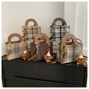 Detail of five houndstooth tote bags with plush eye pendants and leather handles