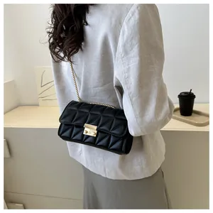 Détail d'un sac bandoulière matelassé noir avec chaîne dorée porté par un mannequin