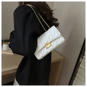 Détail d'un sac matelassé blanc avec fermoir doré carré et bandoulière en chaîne