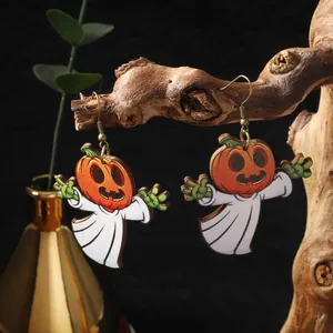 Detailed close-up of wooden pumpkin and ghost earrings hanging on a natural branch