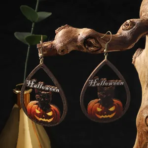Dettaglio di orecchini di Halloween in legno con zucca e gatto appesi a un ramo