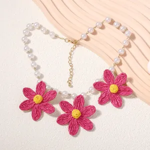 Dettaglio collana margherita in rafia rosa tessuta con perle e catena dorata