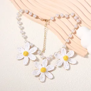 Dettaglio della collana di perle con margherite in rafia e chiusura dorata