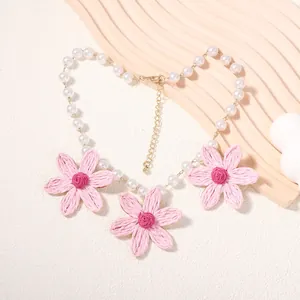 Dettaglio collana di perle con fiori di margherita in raffia rosa e chiusura dorata