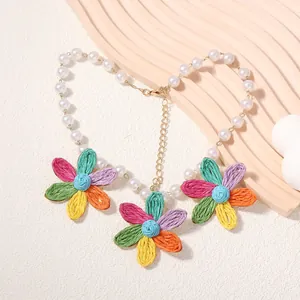 Dettaglio macro della collana con margherite tessute colorate e perle bianche