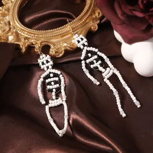 Detail of handmade beaded skull skeleton earrings on elegant vintage silk background