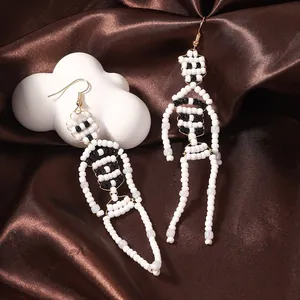 Macro detail of handmade beaded skeleton earrings on dark brown silk background